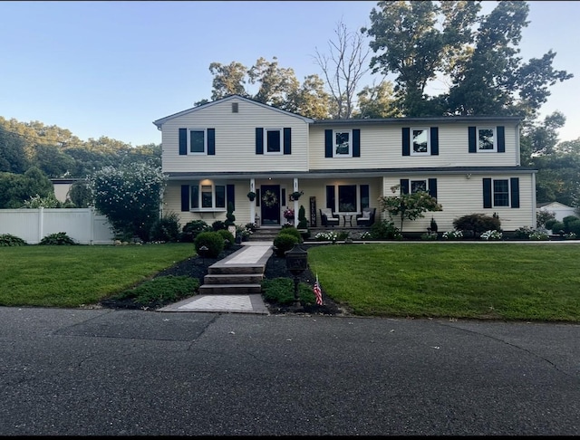 view of front of house with a front lawn, a porch, and fence