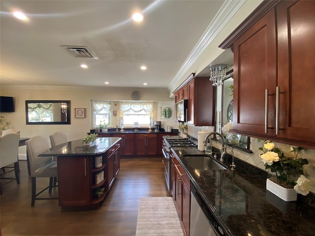 kitchen with a sink, a breakfast bar area, stainless steel appliances, backsplash, and visible vents