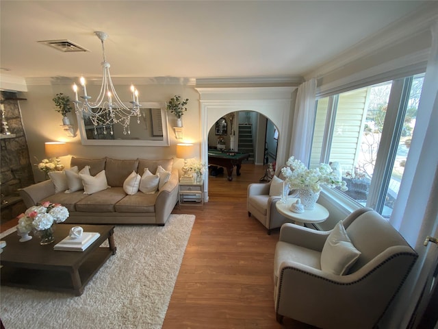 living room with arched walkways, a chandelier, wood finished floors, visible vents, and ornamental molding