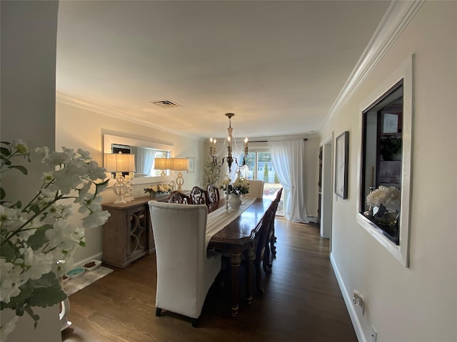 dining area featuring visible vents, crown molding, dark wood finished floors, baseboards, and a chandelier