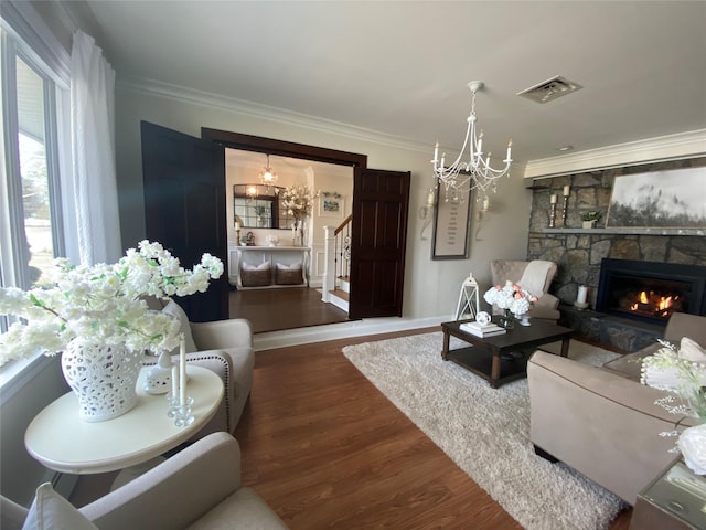 living area with visible vents, crown molding, wood finished floors, and a notable chandelier