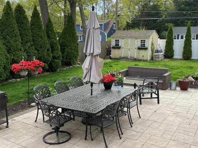 view of patio / terrace with a fenced backyard, a storage unit, an outbuilding, and outdoor dining area
