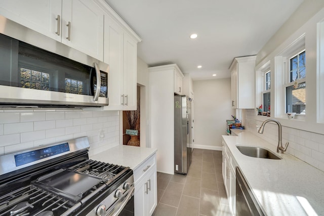 kitchen featuring stainless steel appliances, plenty of natural light, white cabinets, and a sink