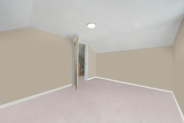 additional living space featuring lofted ceiling, light colored carpet, and baseboards