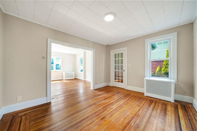 spare room with baseboards, wood-type flooring, and radiator