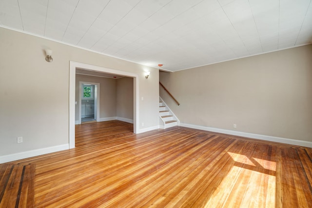 unfurnished room featuring light wood finished floors, stairs, and baseboards