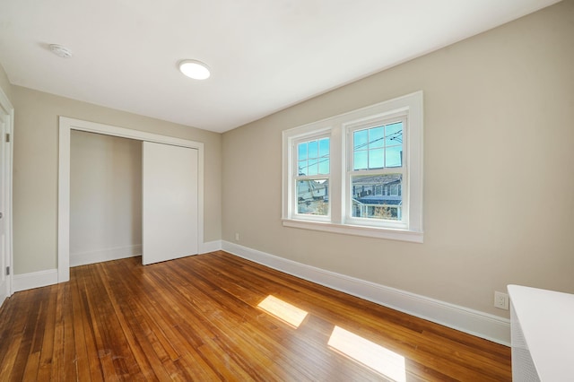 unfurnished bedroom with hardwood / wood-style floors, a closet, and baseboards