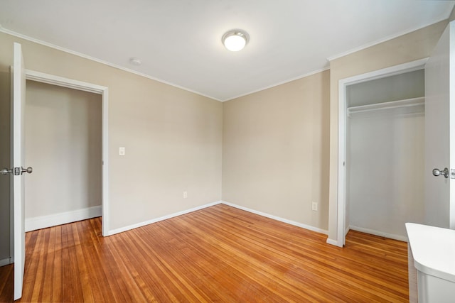 unfurnished bedroom with light wood-type flooring, a closet, baseboards, and crown molding