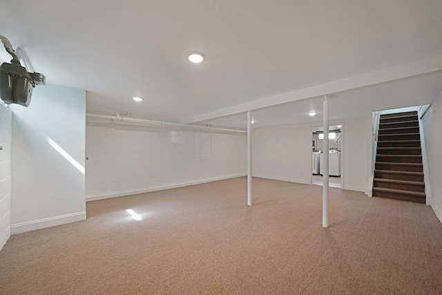 finished below grade area featuring stairs, washer and clothes dryer, concrete block wall, and recessed lighting