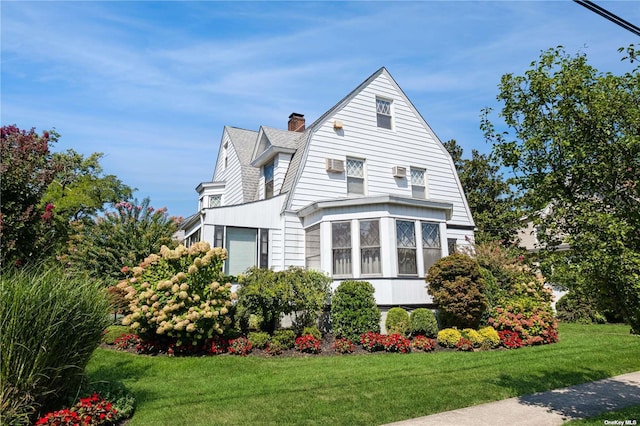 view of front of property featuring a front lawn, a chimney, and a gambrel roof