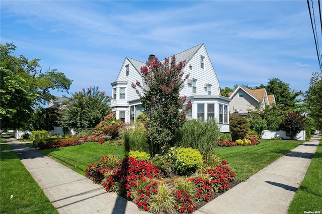 view of front facade featuring a chimney and a front lawn