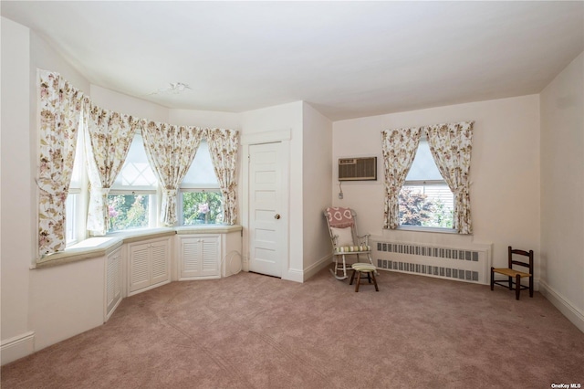 living area with radiator, light colored carpet, plenty of natural light, and an AC wall unit