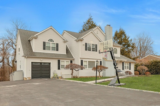 traditional home with a garage, a shingled roof, driveway, a front lawn, and a chimney