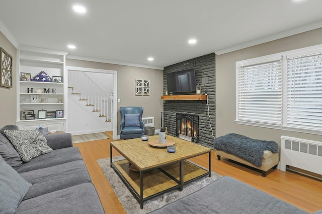 living area with radiator heating unit, visible vents, stairway, and crown molding