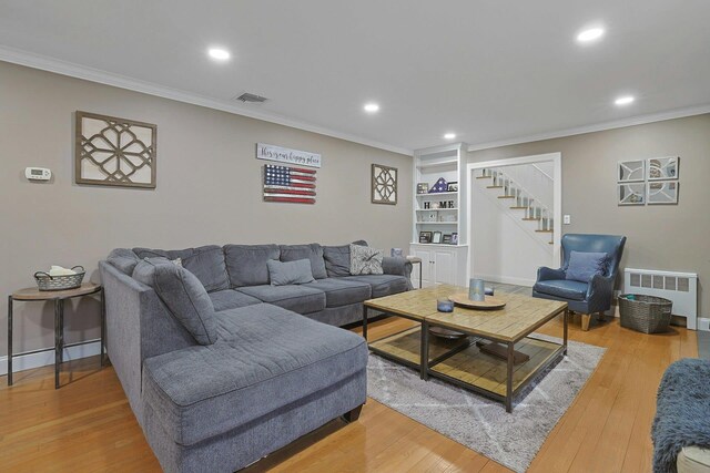 living room with visible vents, crown molding, and light wood finished floors