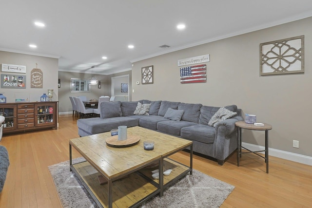 living room with light wood-type flooring, crown molding, and baseboards