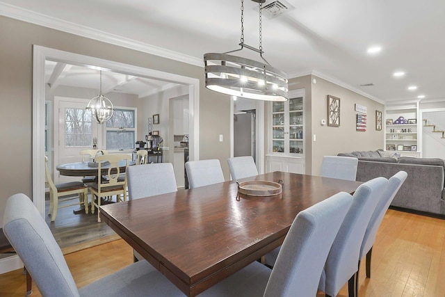 dining area featuring visible vents, crown molding, light wood-style flooring, and stairs