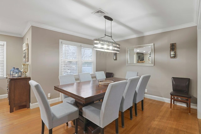 dining space featuring baseboards, light wood finished floors, visible vents, and crown molding