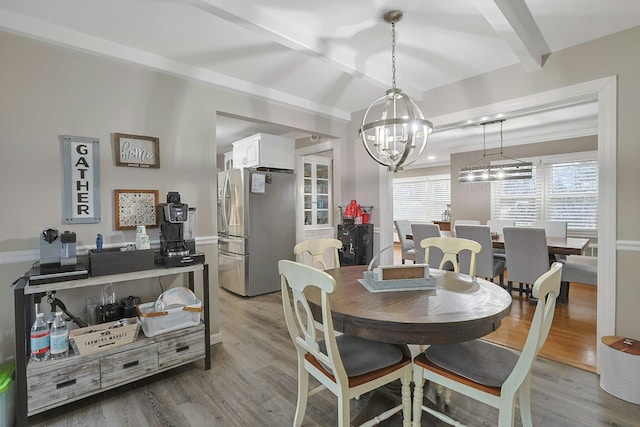 dining space featuring light wood-type flooring, beam ceiling, and a notable chandelier