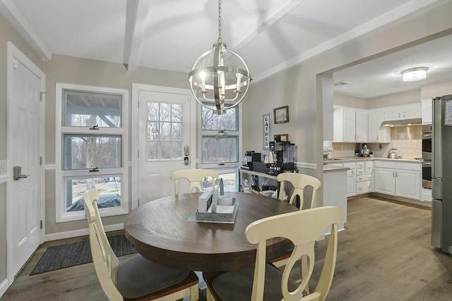 dining space with light wood-type flooring, beam ceiling, visible vents, and a notable chandelier