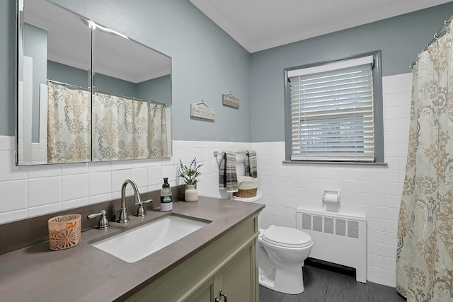 full bath with toilet, vanity, tile walls, wainscoting, and radiator heating unit