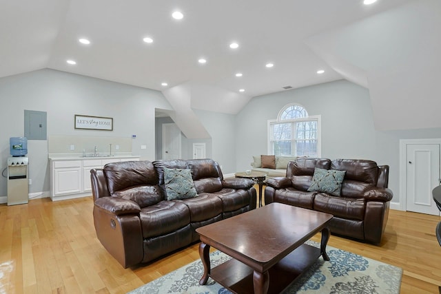 living room featuring lofted ceiling, recessed lighting, light wood-style flooring, and electric panel