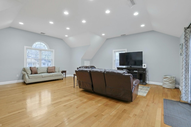 living area with vaulted ceiling, light wood finished floors, and visible vents