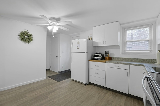 kitchen featuring baseboards, light wood-type flooring, freestanding refrigerator, and white cabinets