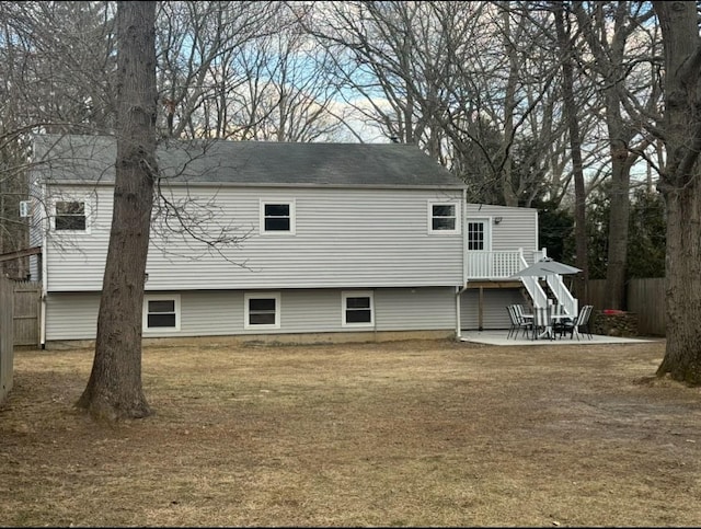 rear view of property featuring fence, a lawn, and a patio