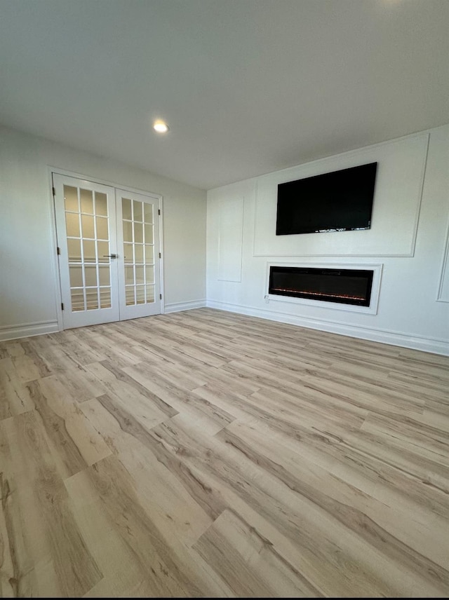 unfurnished living room with french doors, a fireplace, recessed lighting, wood finished floors, and baseboards