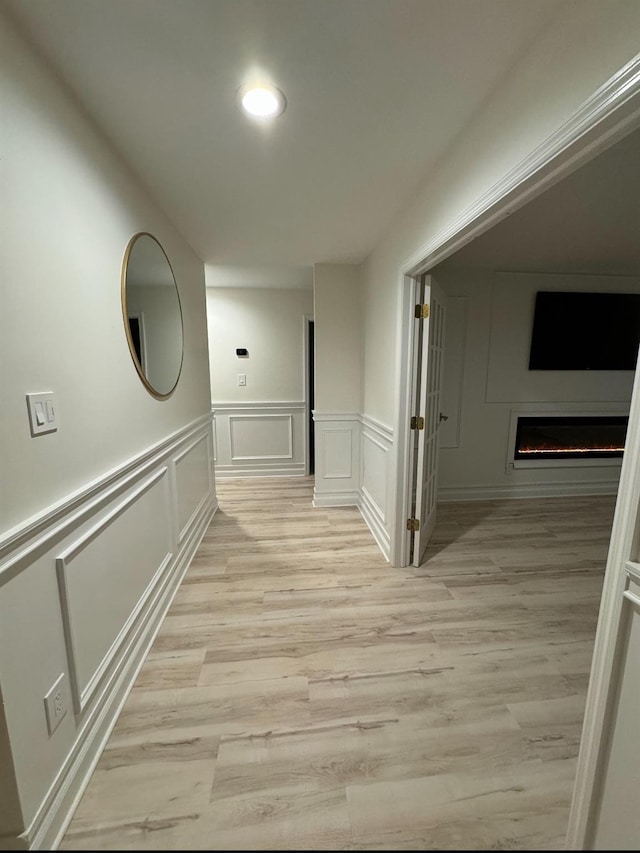 hallway featuring light wood-style floors and a decorative wall