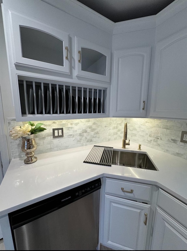 kitchen featuring light countertops, dishwasher, backsplash, and a sink