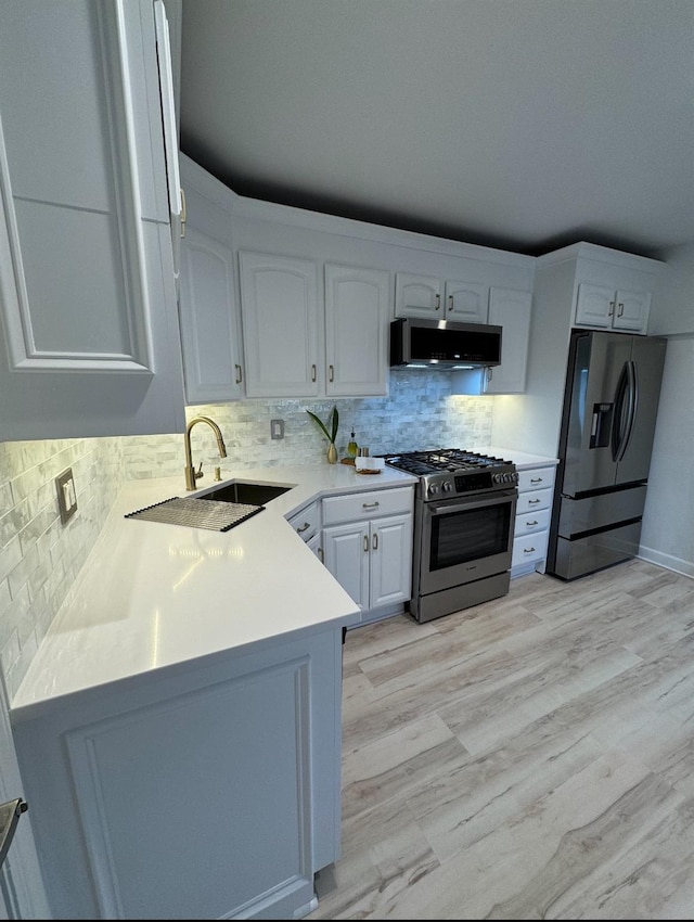 kitchen with range hood, stainless steel appliances, light countertops, white cabinetry, and a sink