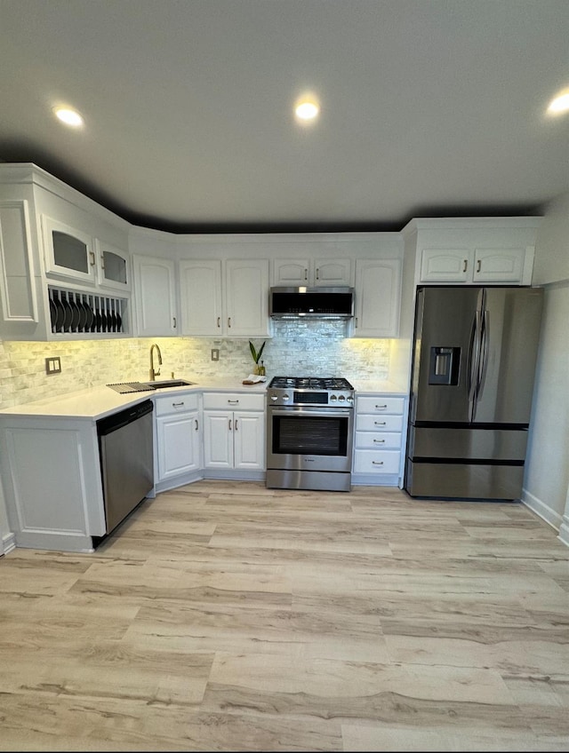 kitchen with white cabinets, extractor fan, stainless steel appliances, and a sink