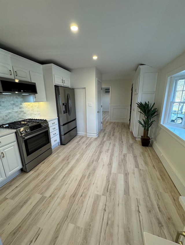 kitchen featuring white cabinets, range hood, tasteful backsplash, and stainless steel appliances