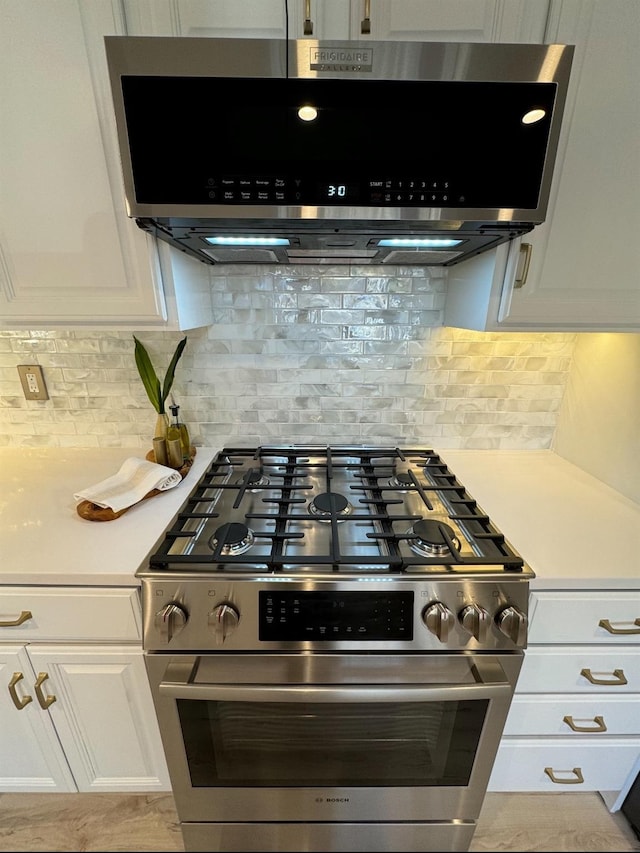 kitchen with white cabinets, gas range, range hood, and light countertops