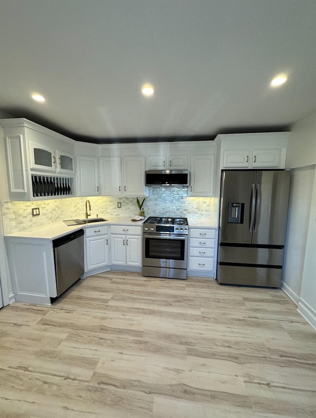 kitchen with stainless steel appliances, light countertops, white cabinets, a sink, and extractor fan