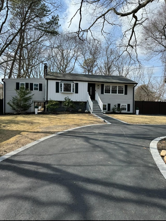 view of front of home with fence, a chimney, and a front lawn