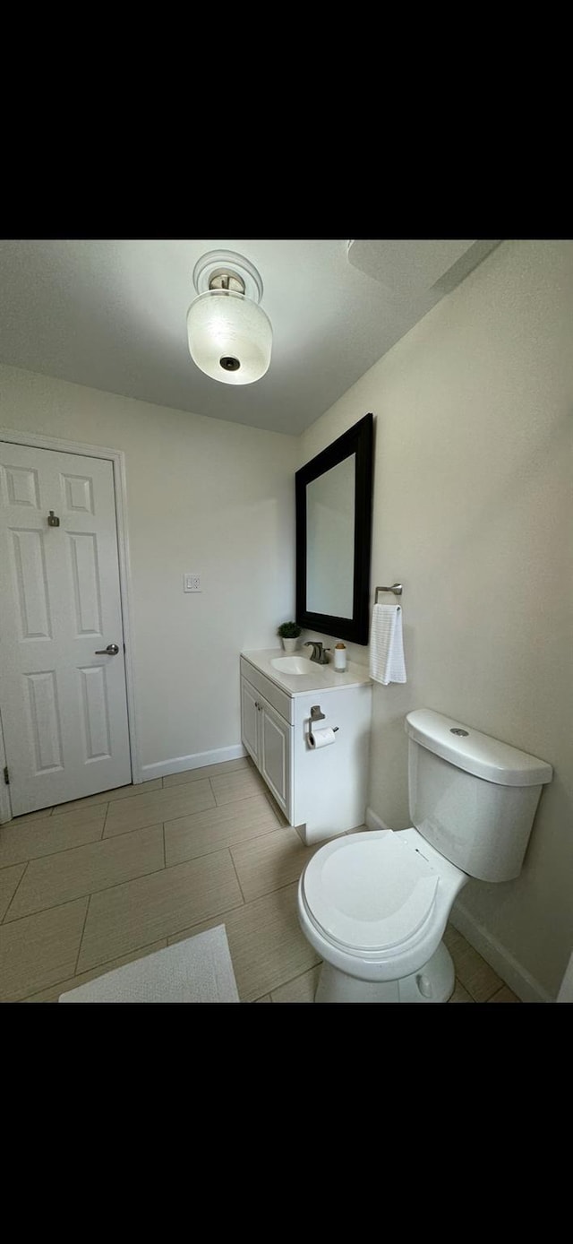 half bathroom with toilet, baseboards, and vanity