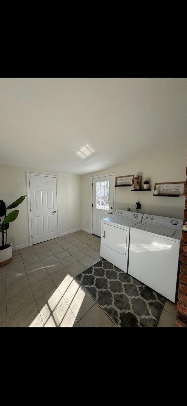 washroom with light tile patterned floors, laundry area, washer and clothes dryer, and baseboards