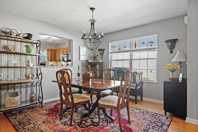 dining area featuring an inviting chandelier, light wood-style flooring, and baseboards