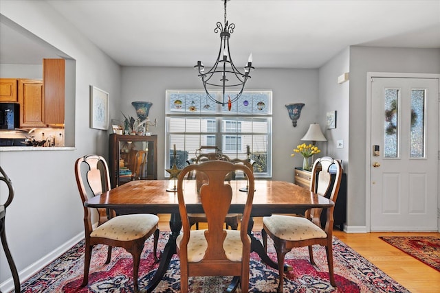 dining room with light wood-type flooring, baseboards, a chandelier, and a wealth of natural light