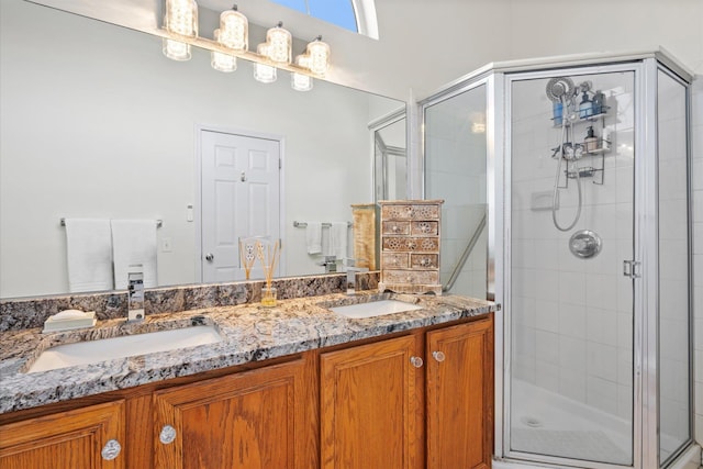 bathroom featuring double vanity, a stall shower, and a sink