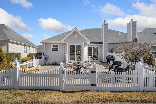 back of house with a shingled roof, a patio area, and a fenced backyard