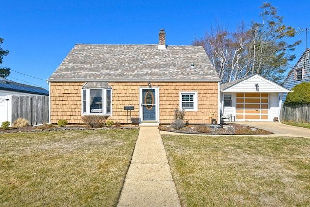 view of front of house with a detached garage, concrete driveway, a front lawn, and fence