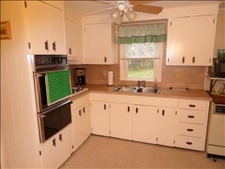 kitchen with white cabinets, oven, a sink, and dishwasher