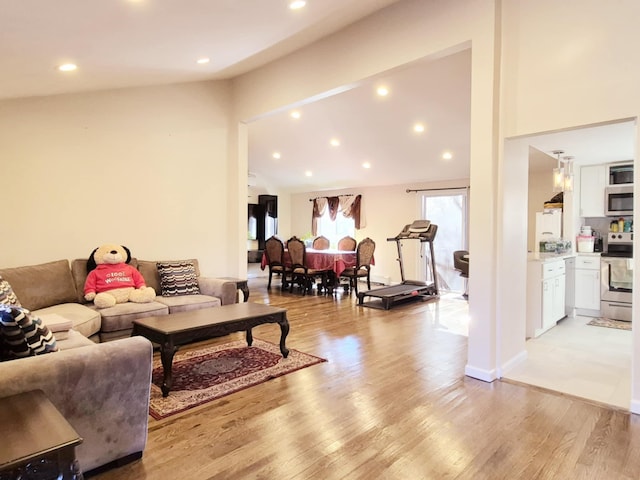 living room with baseboards, high vaulted ceiling, light wood-style flooring, and recessed lighting