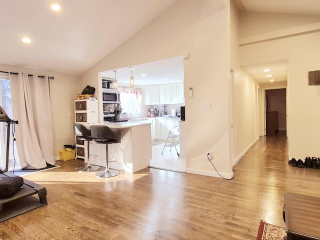 living room featuring baseboards, light wood finished floors, recessed lighting, and a healthy amount of sunlight