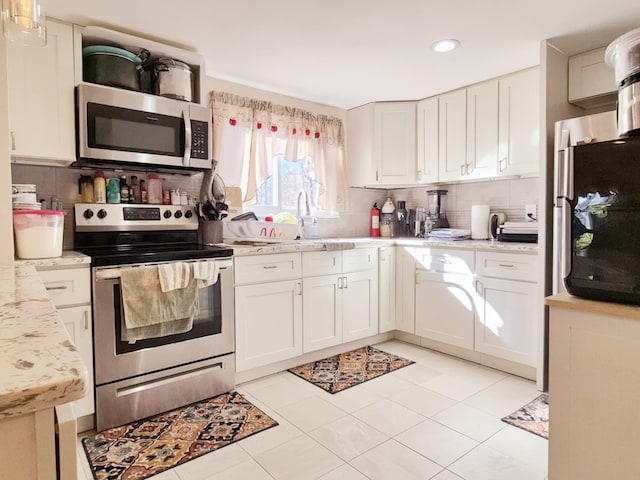 kitchen featuring stainless steel appliances, tasteful backsplash, a sink, and white cabinetry