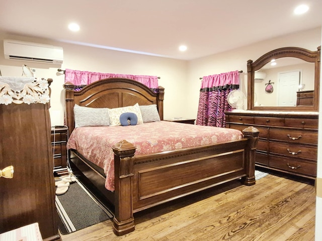 bedroom featuring light wood finished floors, a wall unit AC, and recessed lighting